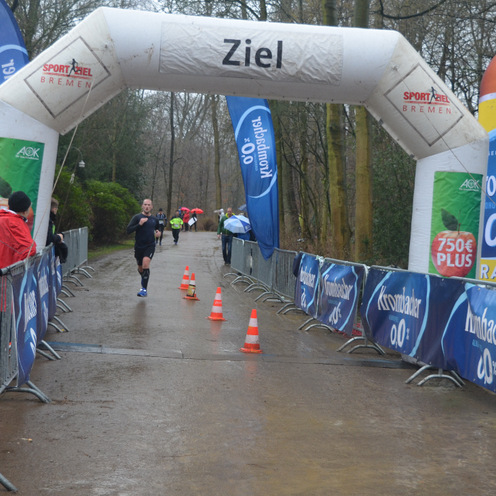 Die Ziellinie im Vordergrund und es ist ein L&auml;ufer im Hintergrund zu sehen.