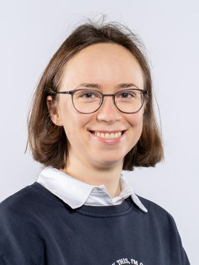 Auf dem Foto ist Isabel Tanzberger zusehen. Sie hat kinnlanges braunes Haar. Sie tr&auml;gt eine runde Brille und eine wei&szlig;e Bluse unter einem dunkel blauen Pullover.