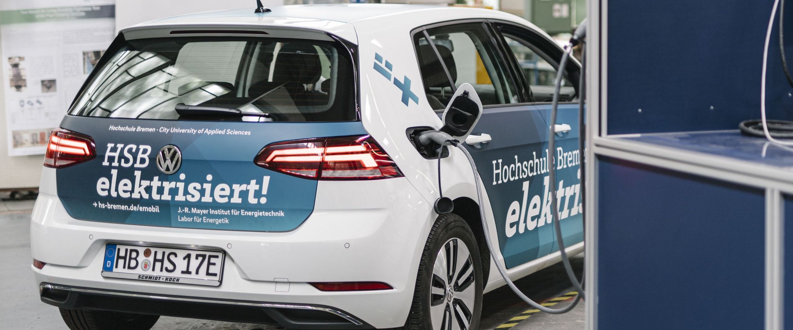 Ein Elektroauto im Branding der Hochschule Bremen wird aufgeladen.