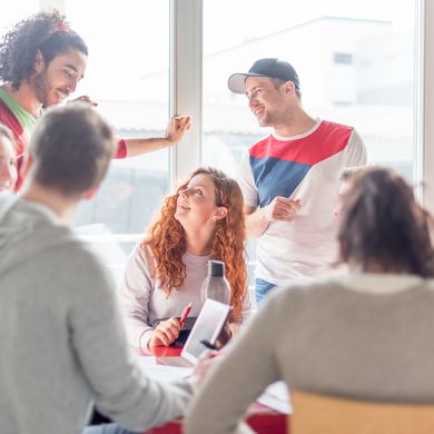 Eine Gruppe von Studierenden unterh&auml;lt sich, einige stehen, andere sitzen. 