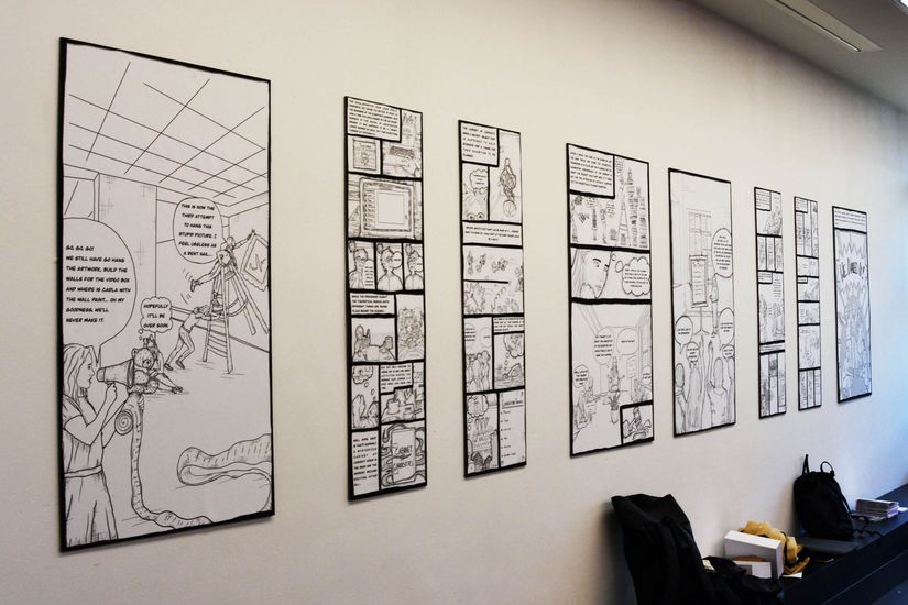 Eine Wand mit gerahmten Bildern von Comic Zeichnungen.