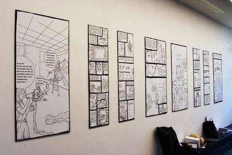 Eine Wand mit gerahmten Bildern von Comic Zeichnungen.