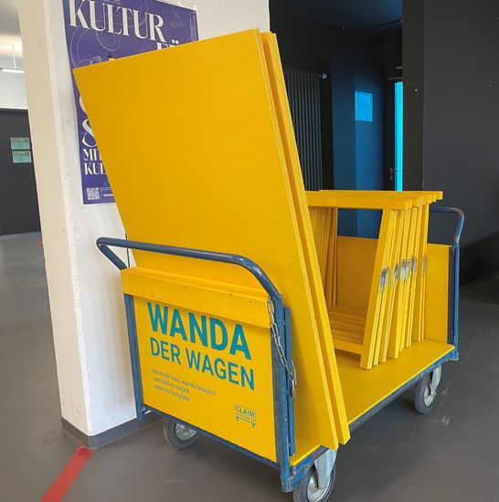 gelber Wagen mit schriftzug "Wanda" mit gelben Brettern und Bauelementen