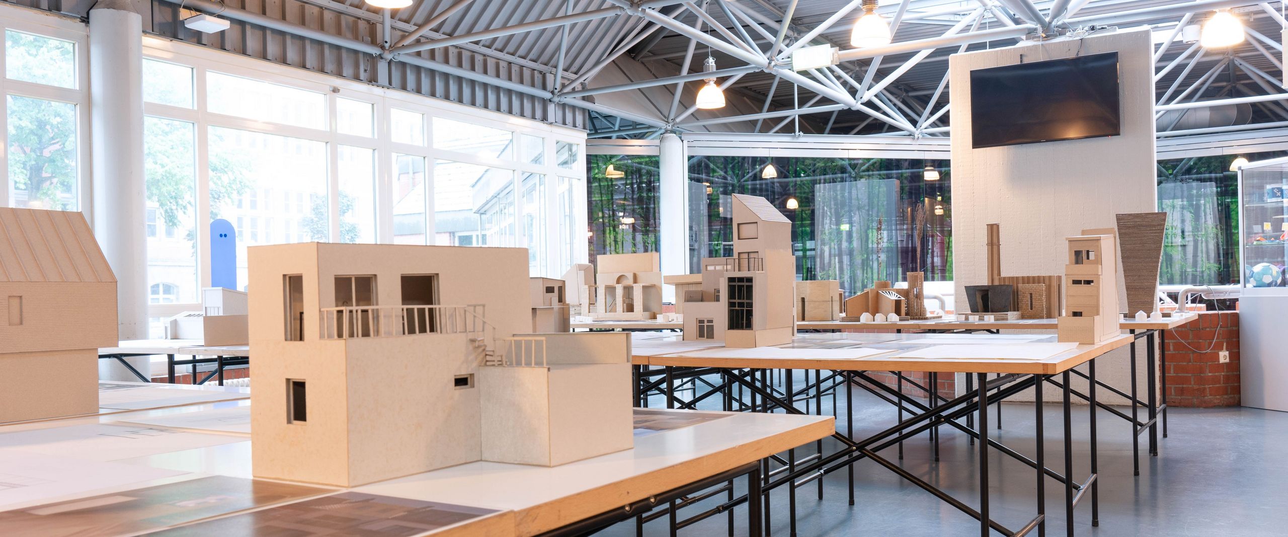 Blick auf eine Ausstellung mit Architekturmodellen auf Tischen