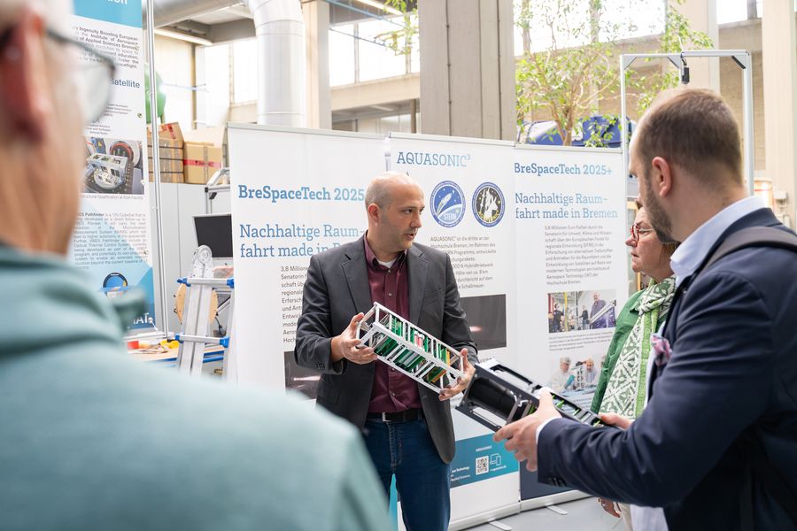 Auf diesem Bild zeigt ein Mann die Prototypen der VIBES Satelliten, die die Gr&ouml;&szlig;e eines Schuhkartons haben. 