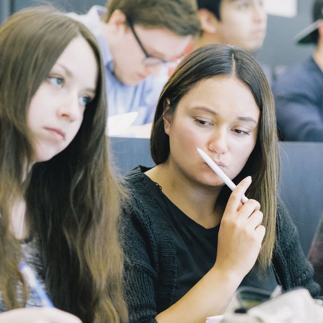 Studierende sitzen nebeneinander in einem Hörsaal.