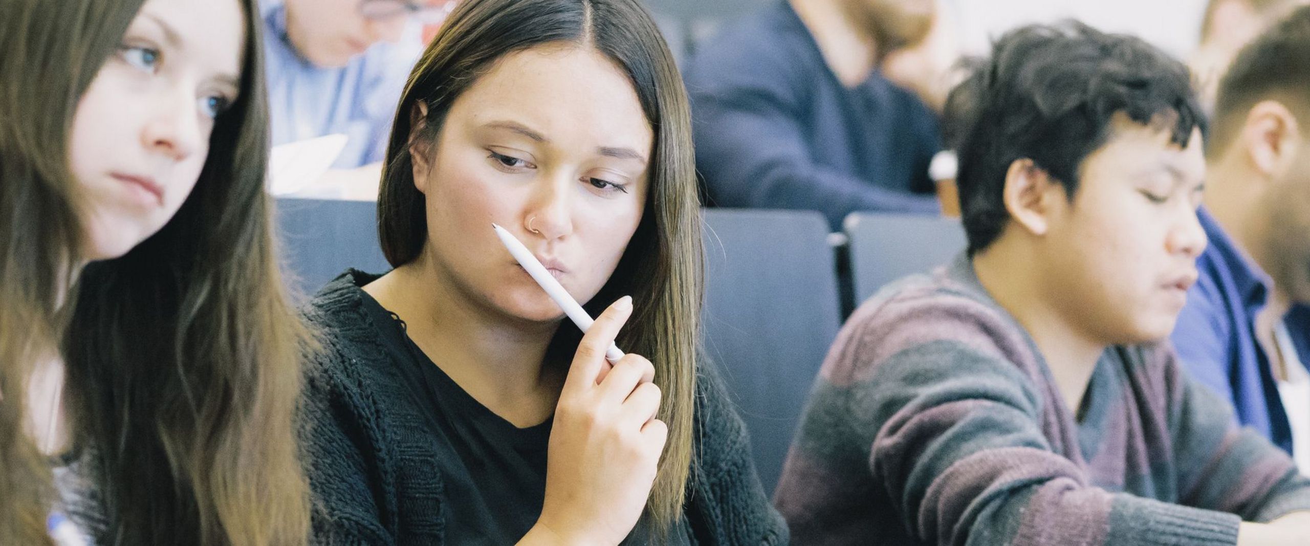 Studierende sitzen nebeneinander in einem Hörsaal.