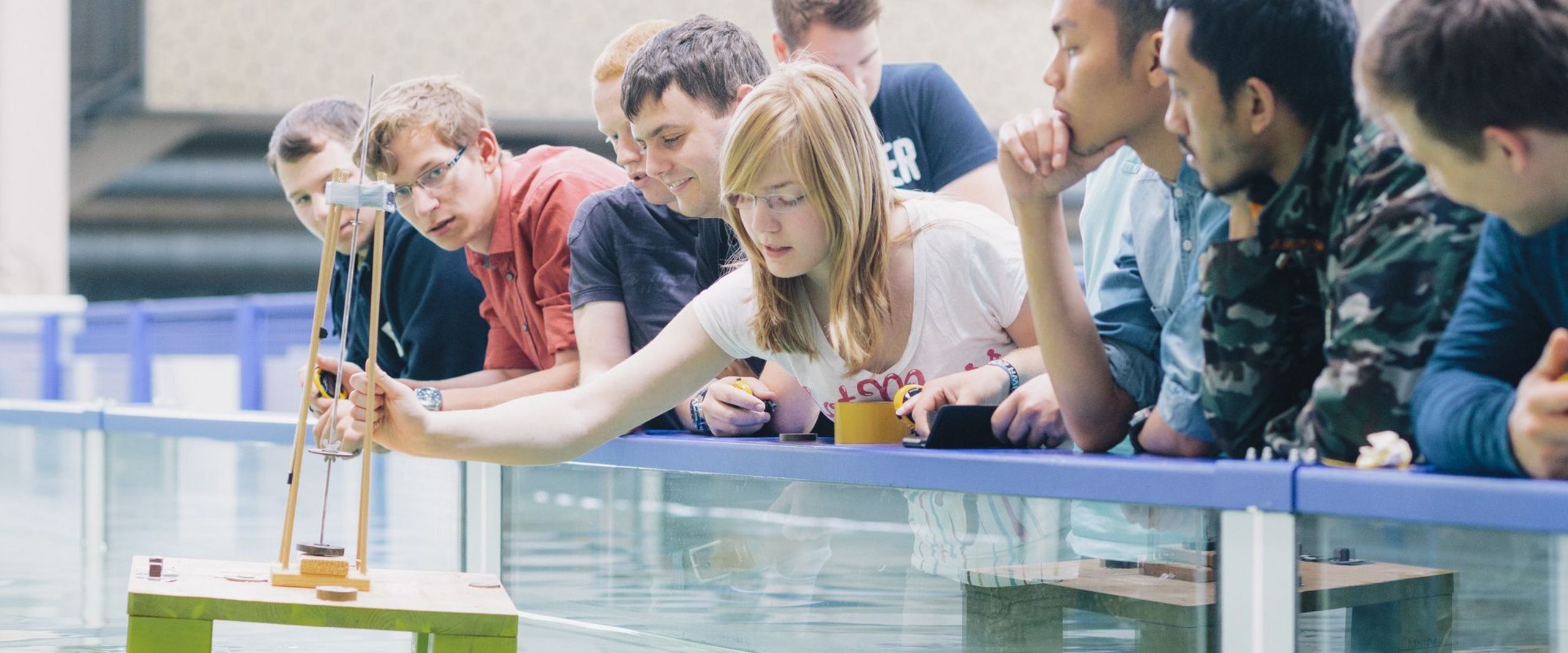 Studierende testen eine schwimmende Konstruktion in einem Wasserbecken.