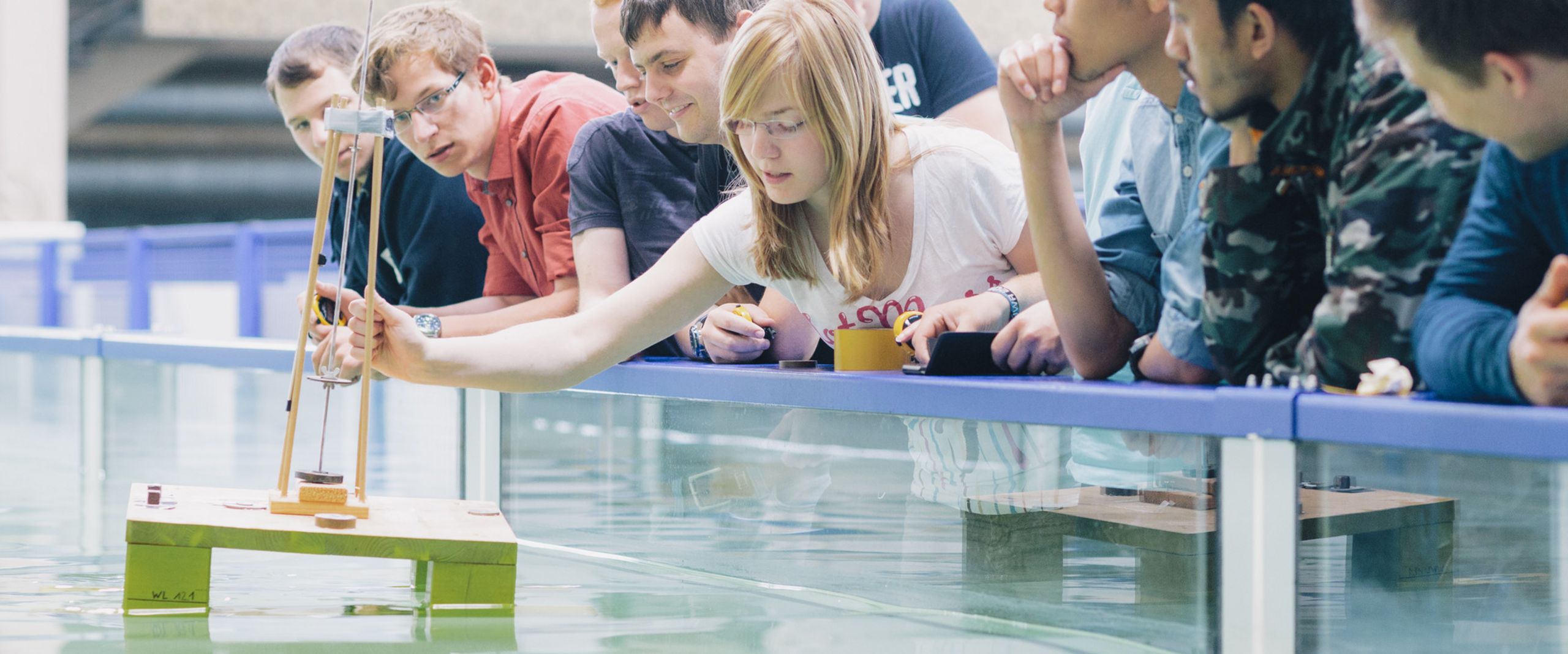 Studierende testen eine schwimmende Konstruktion in einem Wasserbecken.