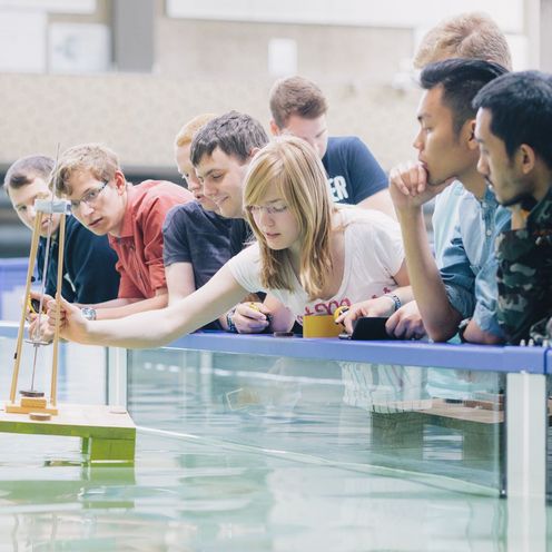 Studierende testen eine schwimmende Konstruktion in einem Wasserbecken.