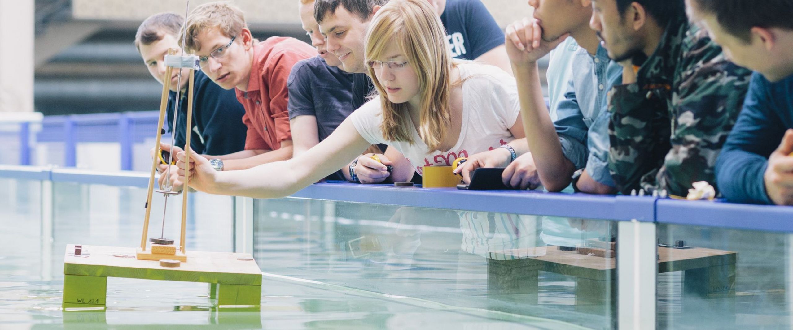 Studierende testen eine schwimmende Konstruktion in einem Wasserbecken.