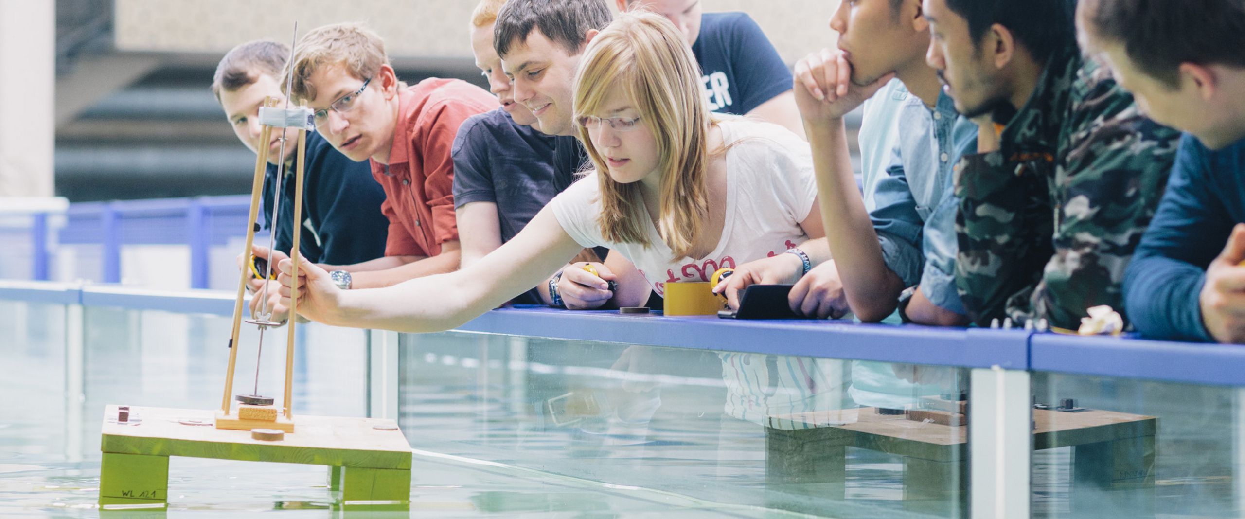 Studierende am Strömungskanal Studierende testen eine schwimmende Konstruktion in einem Wasserbecken.