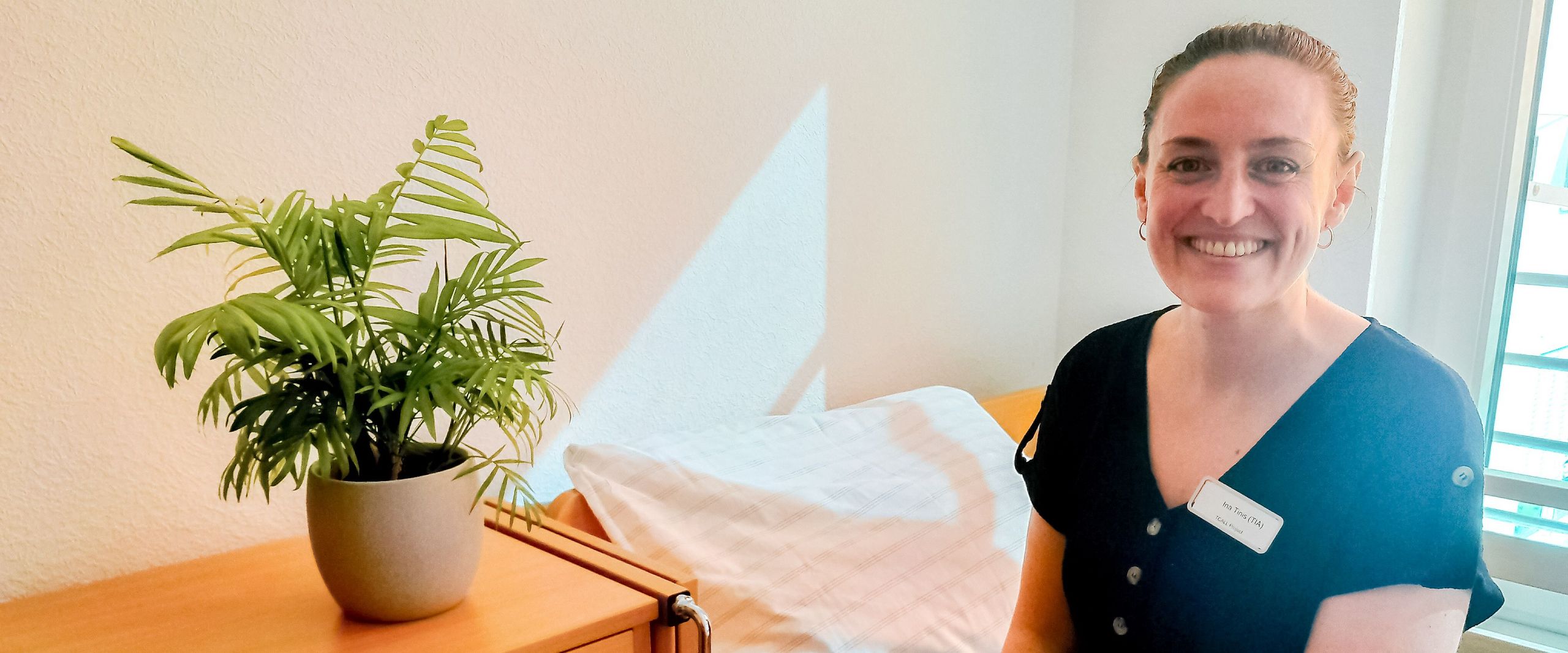 Frau sitzt auf einem Bett und lacht in die Kamera.