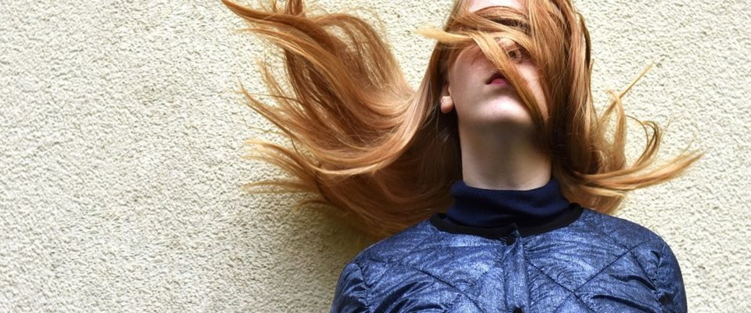 Frau mit langen Haaren, der Gesicht zum Teil von den Haaren verdeckt wird