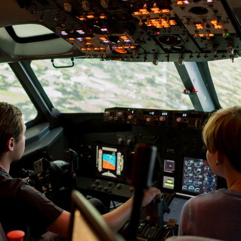 Flugsimulator Zwei Studierende sitzen im Cockpit eines Flugsimulators.