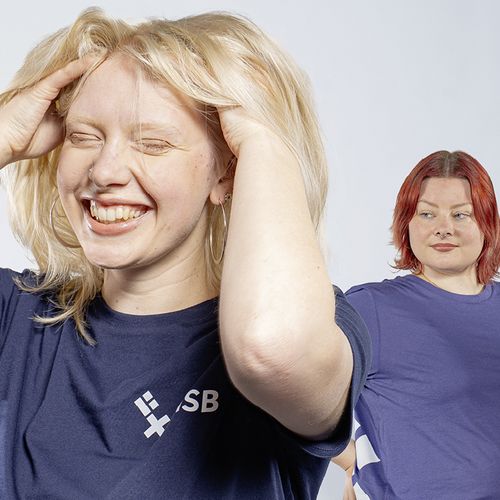 Eine Gruppe Studierende, die T-Shirts und Hoodies in verschiedenen Farben mit HSB-Logo tr&auml;gt-