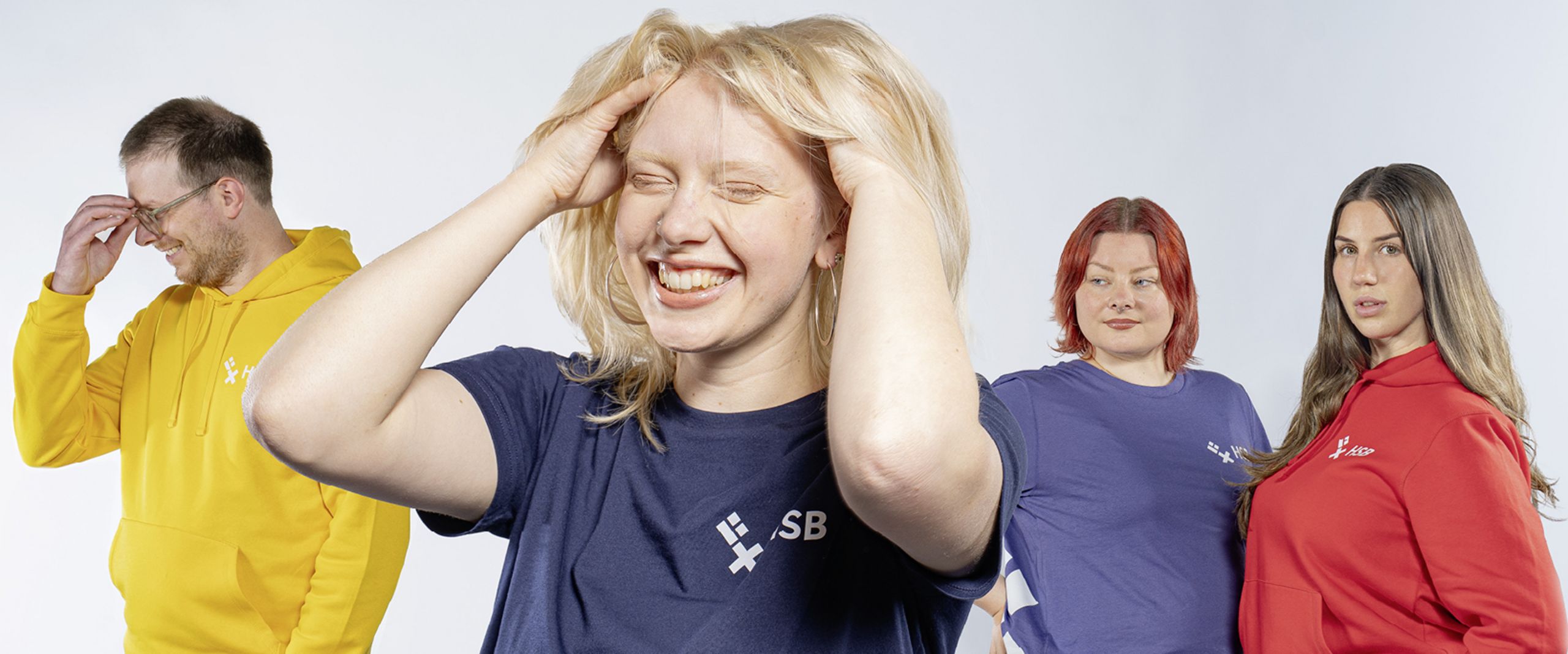 Eine Gruppe Studierende, die T-Shirts und Hoodies in verschiedenen Farben mit HSB-Logo tr&auml;gt-