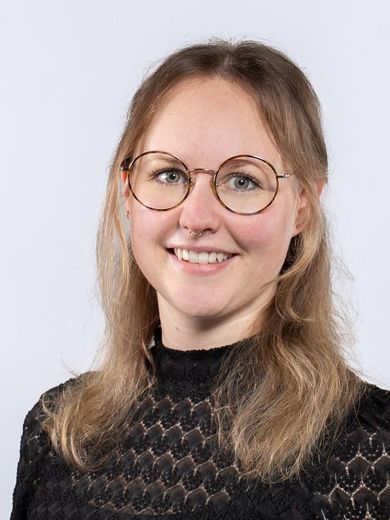 Auf dem Foto ist Karina Westermann zusehen. Sie hat blondes langes Haar. Sie tr&auml;gt eine runde Brille und ein schwarzes Shirt mit hohem Kragen.