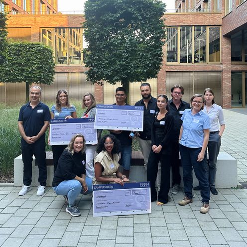 Gruppenbild mit M&auml;nnern und Frauen. Sie lachen und halten gro&szlig;e Checks hoch.
