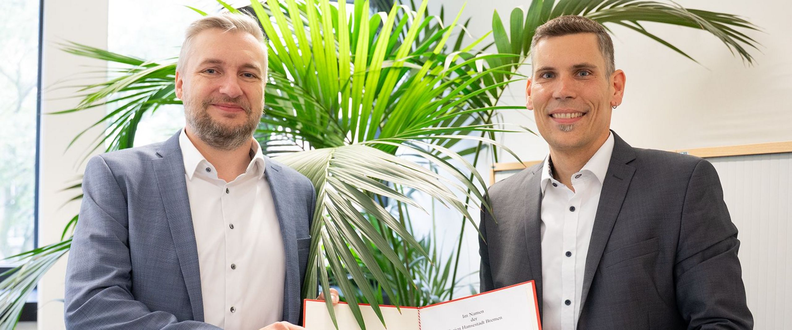 Prof. Dr. Dr. Jan Thiele mit Kanzler der HSB, beide halten die Ernennungsurkunde in ihrer Mitte
