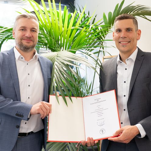 Prof. Dr. Dr. Jan Thiele mit Kanzler der HSB, beide halten die Ernennungsurkunde in ihrer Mitte