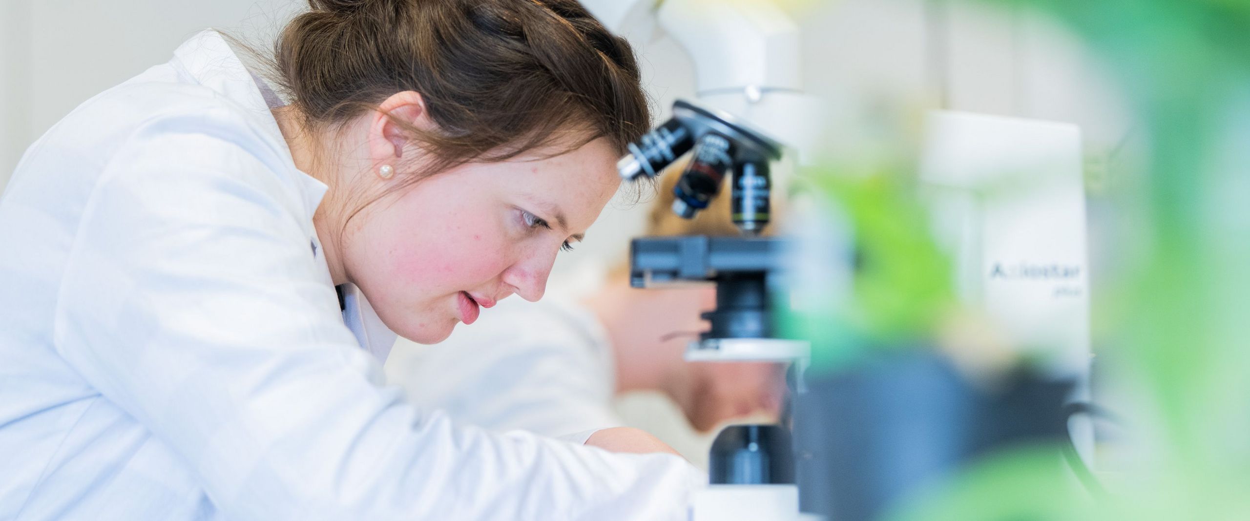 Studentin im Labor mit konzentriertem Blick auf das vorliegende Experiment.