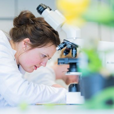 Studentin im Labor mit konzentriertem Blick auf das vorliegende Experiment.