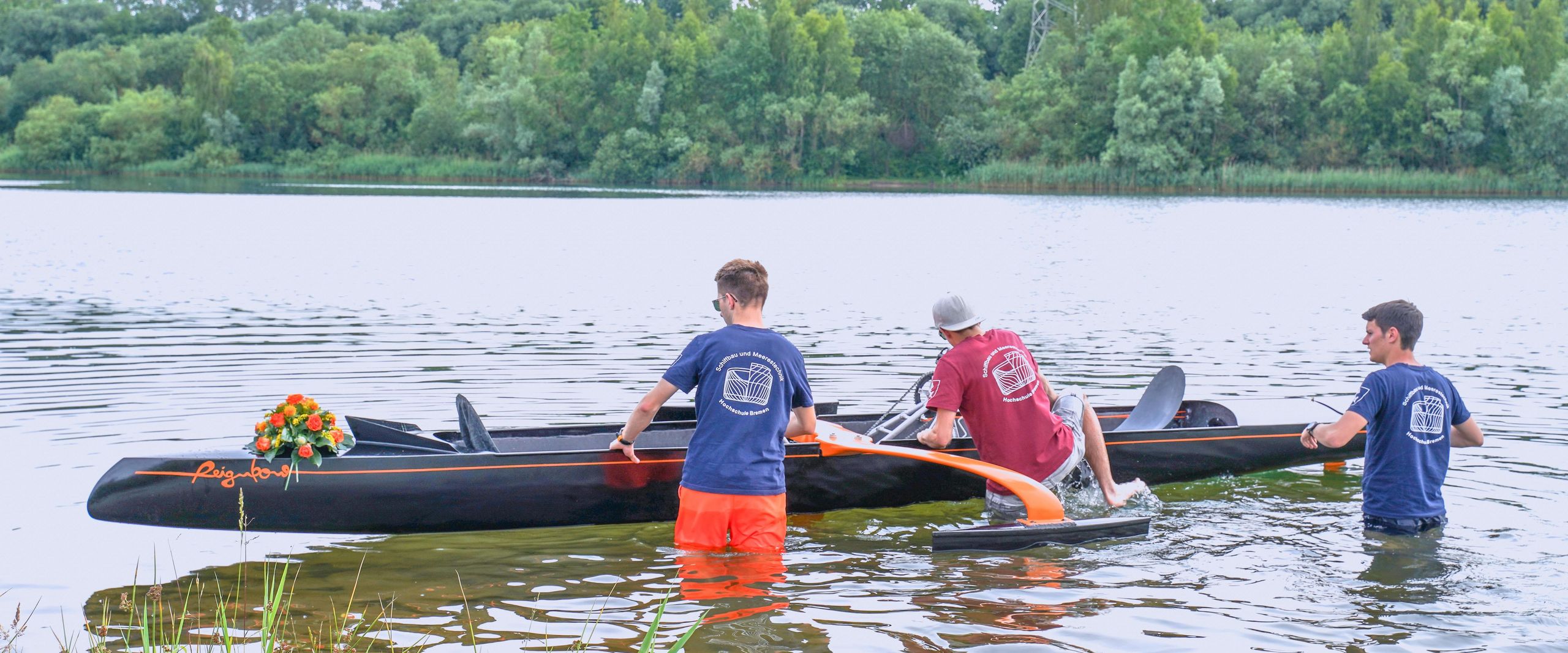 Jungfernfahrt Tretboots Reignbow, das Boot wird von 3 Studierenden zu Wasser gelassen.