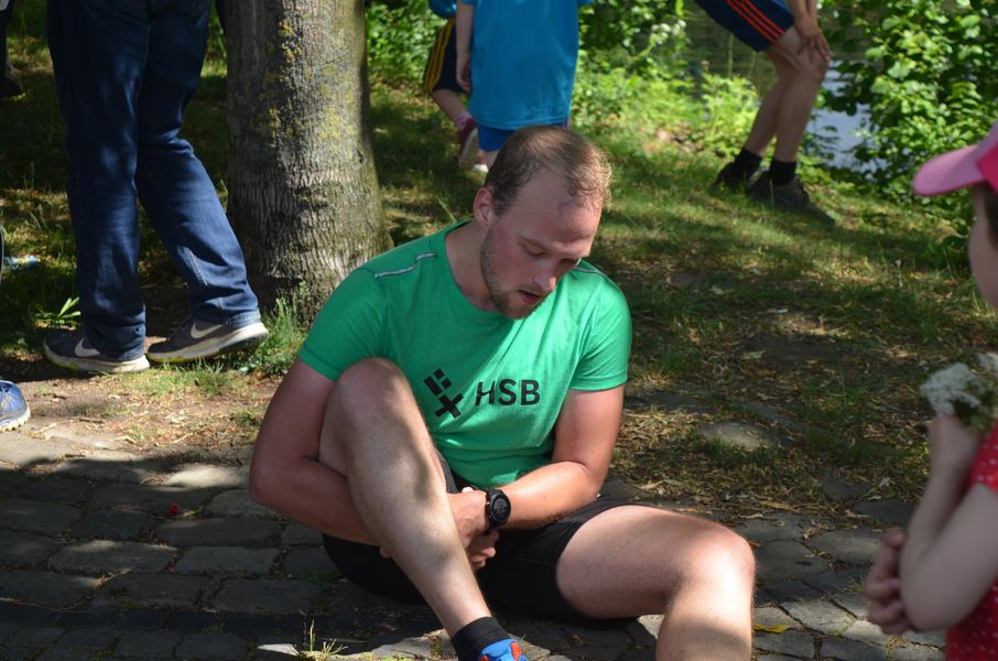 Ein L&auml;ufer sitzt auf einer Wiese.