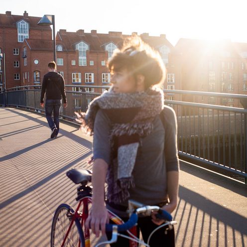 Eine Studentin schiebt ihr Fahrrad.