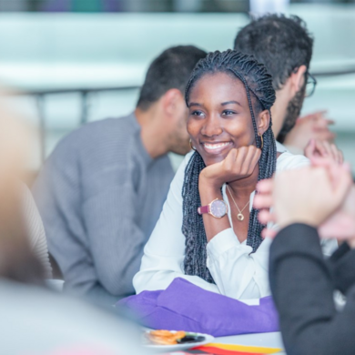Deutsch lernen eine junge Frau lächelt in die Kamera, in der Hand Schreibunterlagen