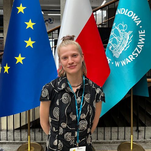 Junge Frau steht vor drei Fahnen