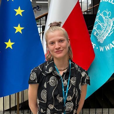 Junge Frau steht vor drei Fahnen