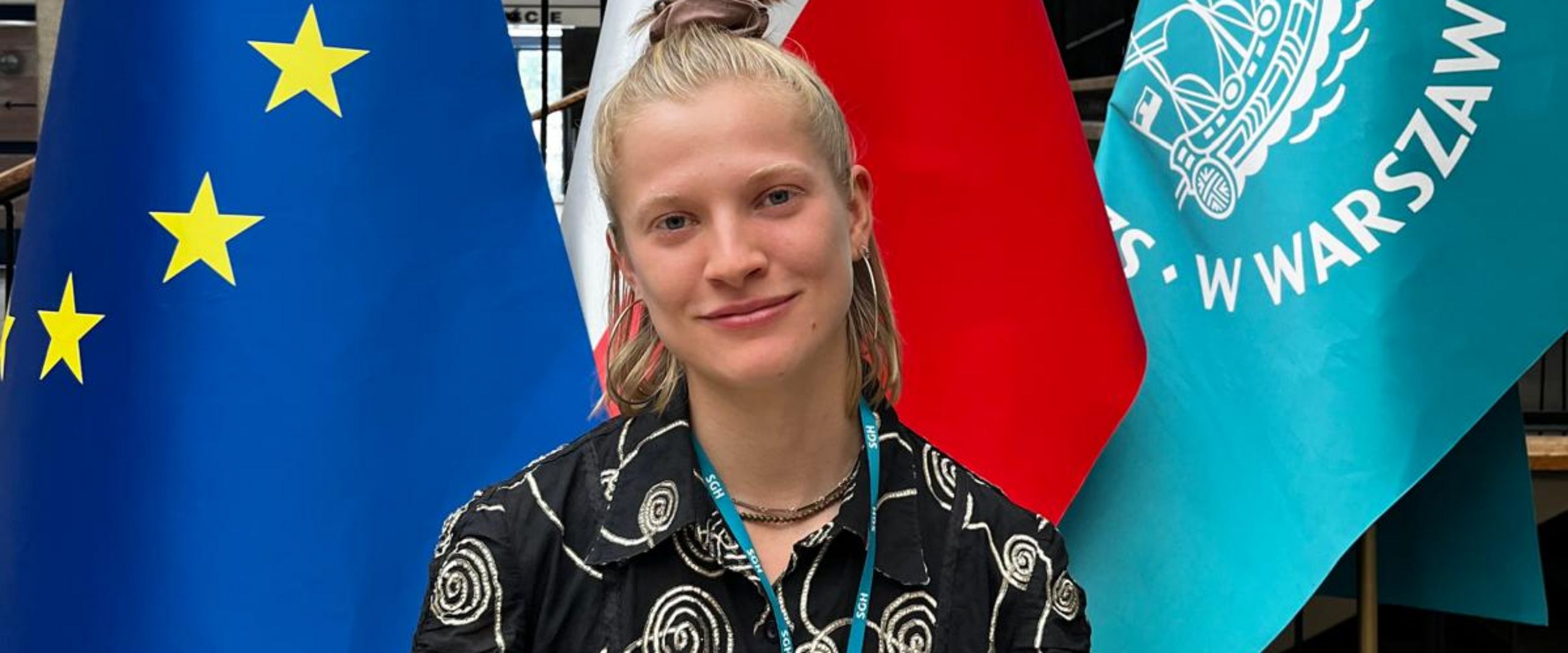 Junge Frau steht vor drei Fahnen