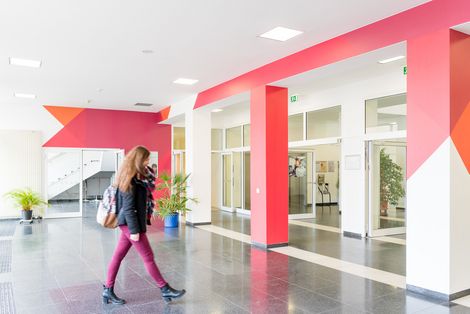 Eine Studentin geht durch das Foyer eines Geb&auml;udes auf dem Campus Flughafenallee.