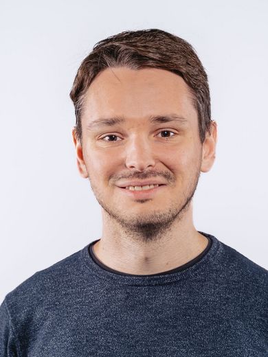 Auf dem Bild ist Alexander Wolotschai zu sehen. Er hat kurzes braunes Haar und einen Drei-Tage-Bart. Er trägt einen dunkelblauen Pullover. 