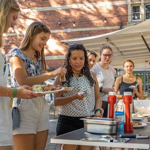 Mehrere HSB Studierende drau&szlig;en vor einem Imbiss Wagen am Tresen und bedienen sich. Hinter dem Tresen steht eine Person und bedient.