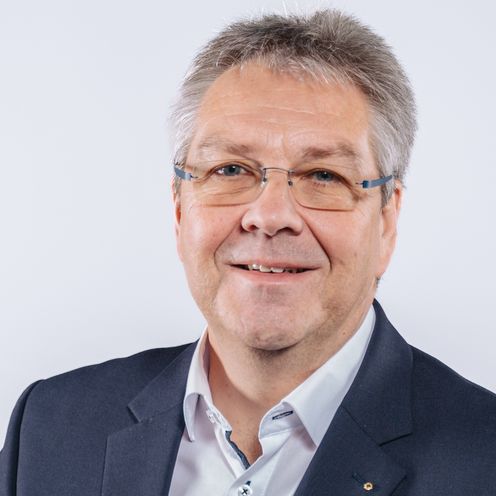 Auf dem Foto ist Helge Ellwart zu sehen. Er hat kurzes graues Haar und tr&auml;gt ein wei&szlig;es Hemd unter einer schwarzen Anzugsjacke. 