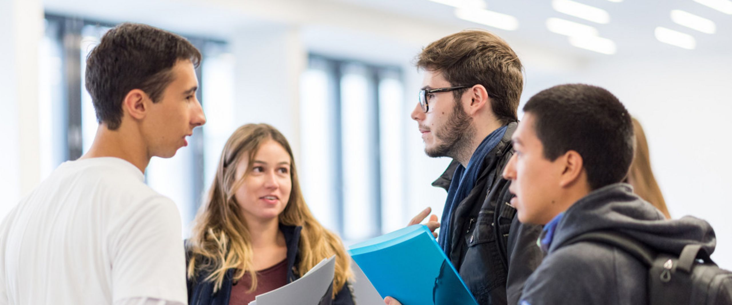 Studierendengruppe Eine Gruppe Studierender mit Unterlagen in der Hand unterhält sich.
