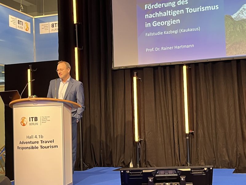 Auf dem Bild ist ein Mann auf einer B&uuml;hne an einem Rednerpult zusehen. 