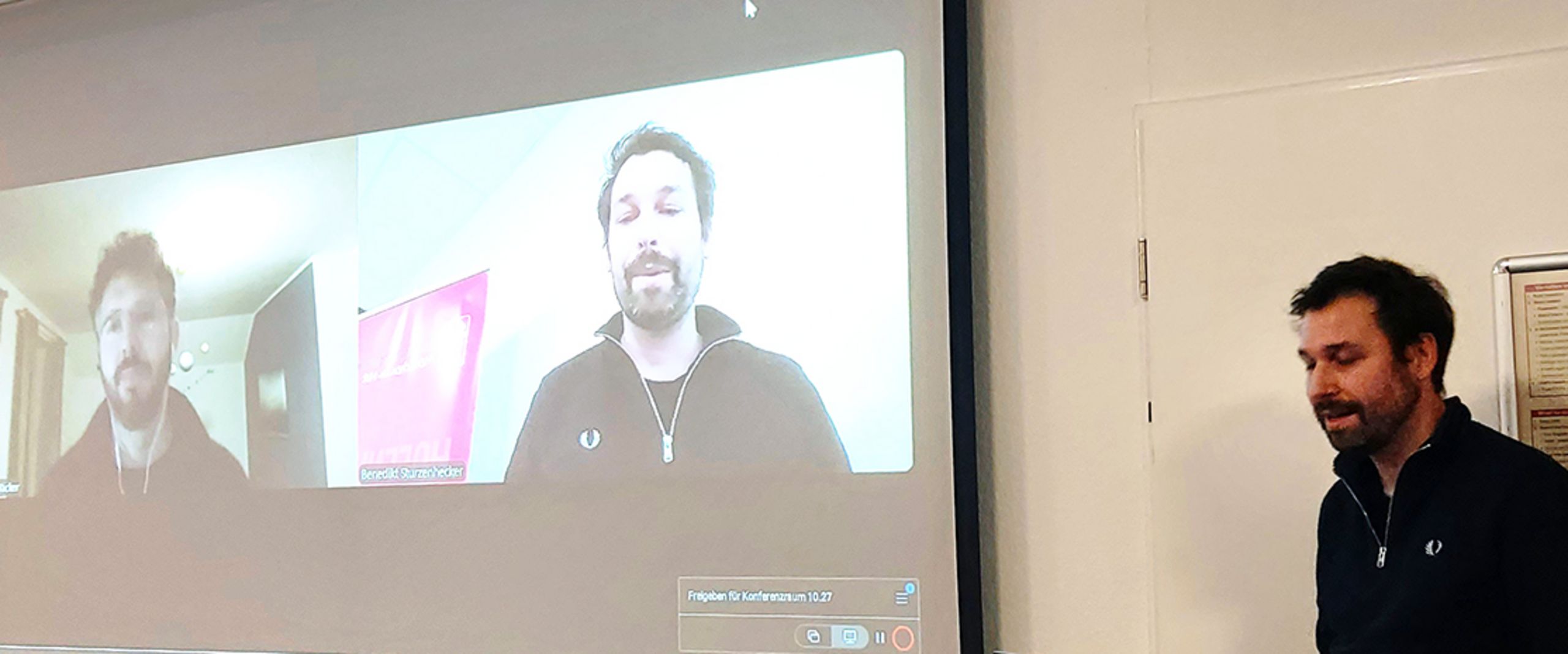 [Translate to English:] 2 Personen auf Leinwand, 1 Person am Rednerpult