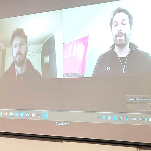 [Translate to English:] 2 Personen auf Leinwand, 1 Person am Rednerpult