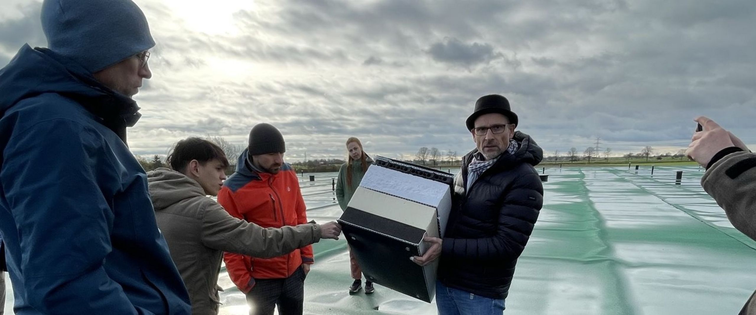 Studierendengruppe bei einer Exkursion auf dem Erdbeckenwärmespeicher in Meldorf (Schleswig-Holstein)