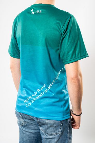 Das Model trägt ein oversized Ombré T-Shirt von türkis bis blau für Herren mit dem HSB-Logo darauf und zeigt sich dabei von hinten.