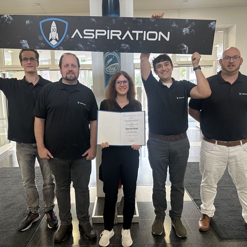 gruppenbild mit vier M&auml;nnern und einer Frau. Sie halten ein Plakat und eine Urkunde.