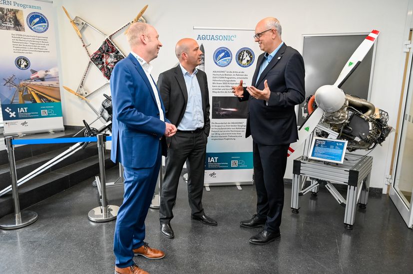 Drei M&auml;nner im Gespr&auml;ch. Im Hintergrund sieht man Flugmodelle.