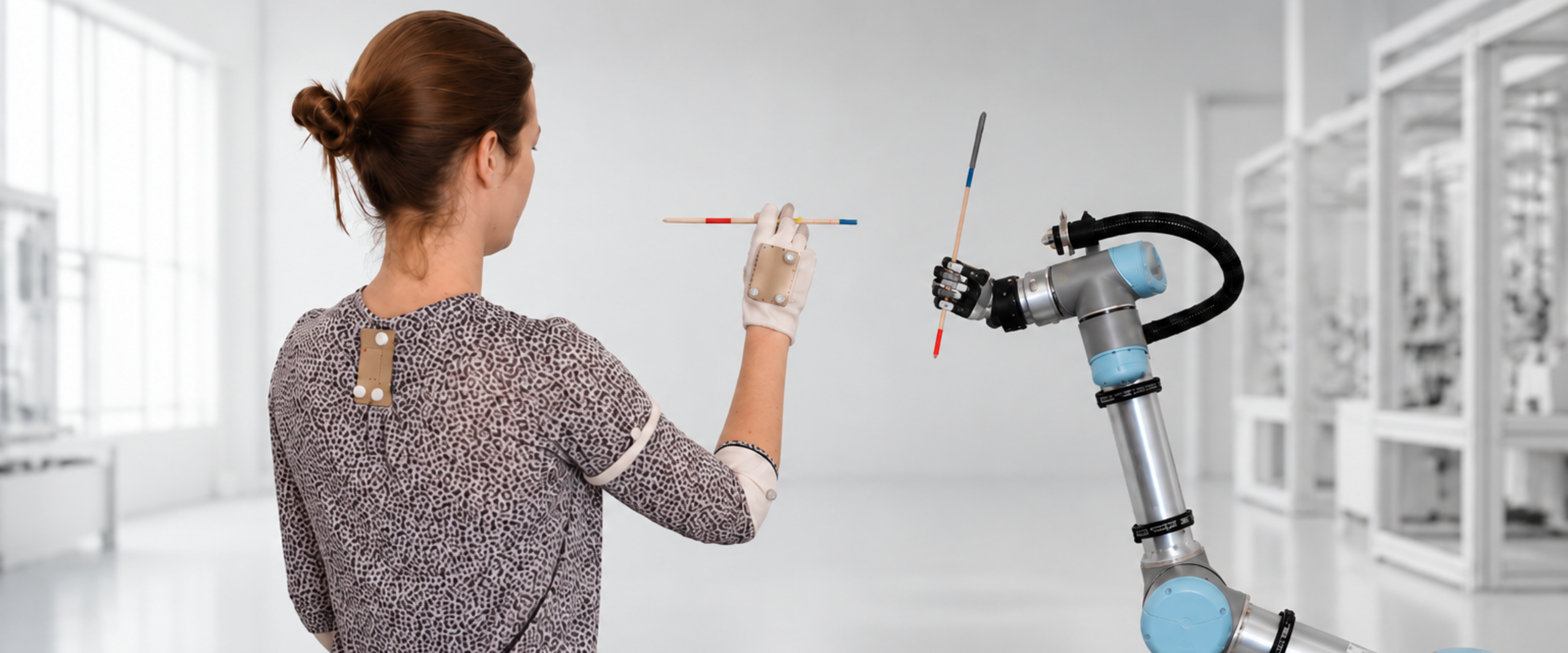 Mensch und Roboter Imitationslernen Eine Frau macht eine Bewegung vor, die per Motiontracking aufgenommen wird. Der Roboterarm lern die Bewegung von der Frau.