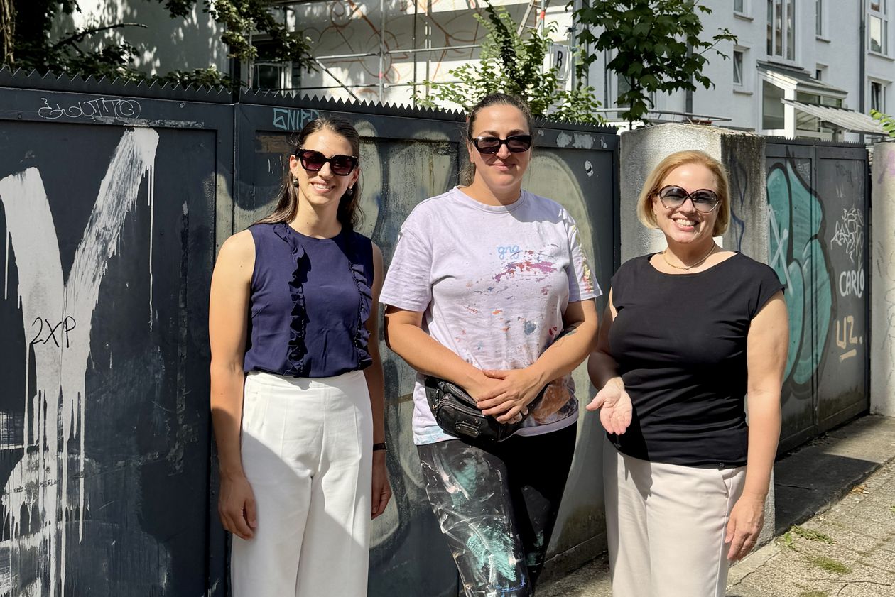 gruppenbild mit drei Frauen vor einer Hausfassade, an der ein Wandbild entsteht
