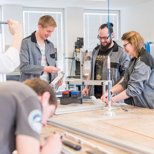 Studierende arbeiten an Bauteilen in einer Werkstatt