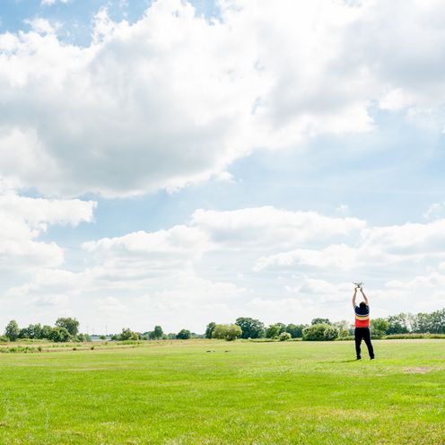 Eine gr&uuml;ne Wiese mit blauem Himmel, welcher teilweise bew&ouml;lkt ist.